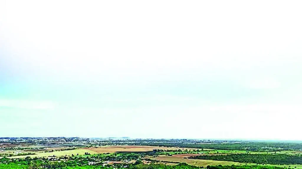 Aerial view showing a mix of developed IT infrastructure and undeveloped land parcels in Kokapet, Hyderabad, under a clear sky.