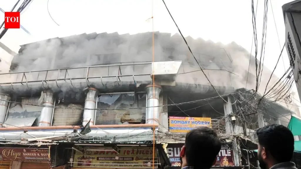 Firefighters with hose lines at a burning commercial building at Madina Circle near Charminar in Hyderabad on Monday