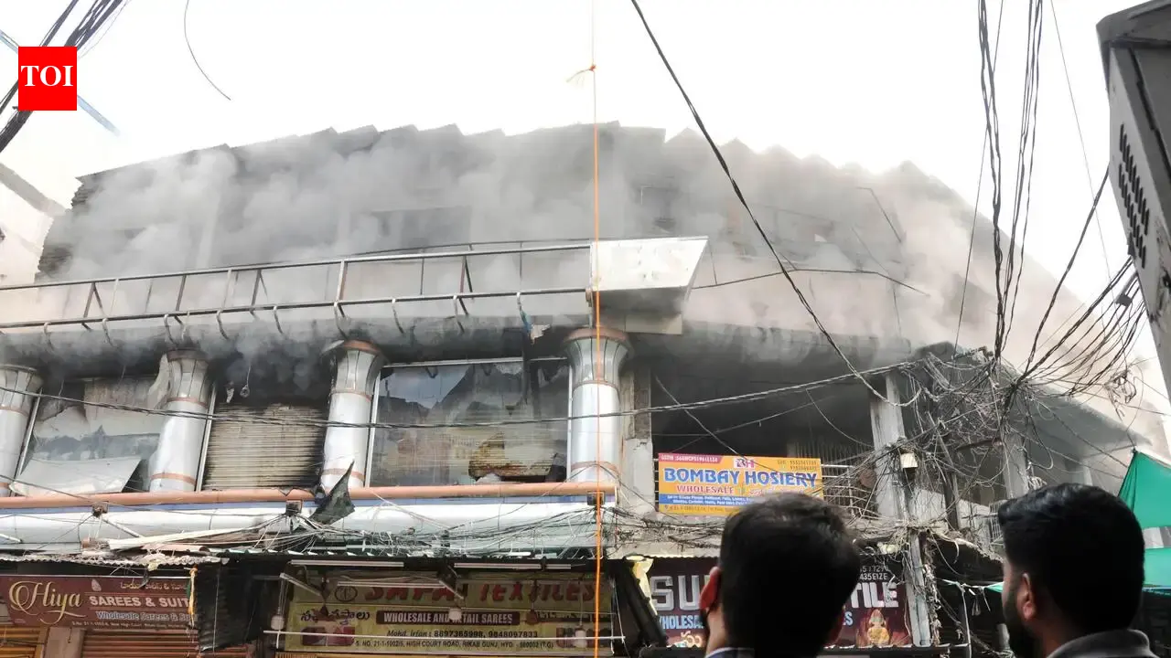 Firefighters with hose lines at a burning commercial building at Madina Circle near Charminar in Hyderabad on Monday
